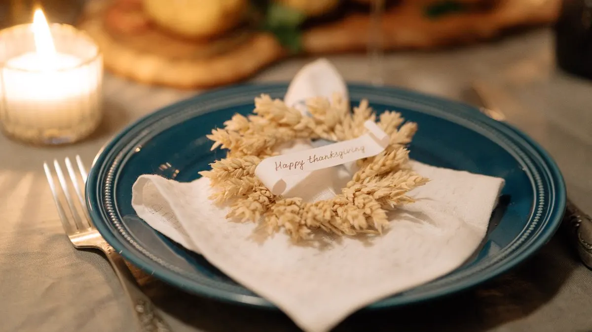 A Thanksgiving place setting with a wheat wreath on a blue plate