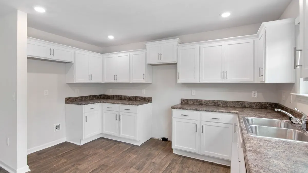 An empty kitchen with white cabinets and bare counters, ready for a move-out clean